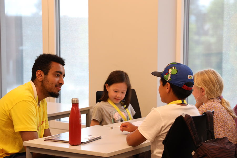 en person og et par barn som sitter ved et bord en person og et par barn som sitter ved et bord